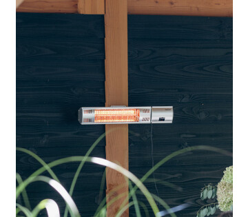 De Sunred Terrasverwarmer Ultra Wand Silver 2000 Watt hangt in de tuin.