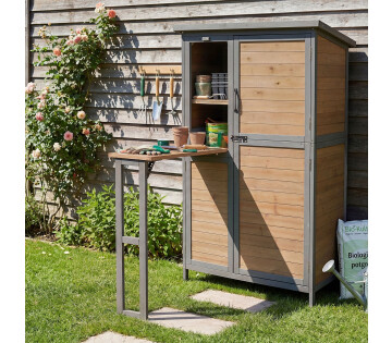 Tuinhuis met uitgeklapte werkbank in houtkleur en grijs frame naast een schutting, ideaal voor tuinwerk en verpotten.