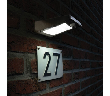 Solar wandlamp verlicht huisnummer op bakstenen muur in het donker