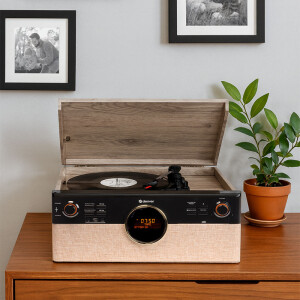 Sfeervolle interieurfoto van de Denver MRD-180 op een houten kast met een vinylplaat, plant en wanddecoratie op de achtergrond.