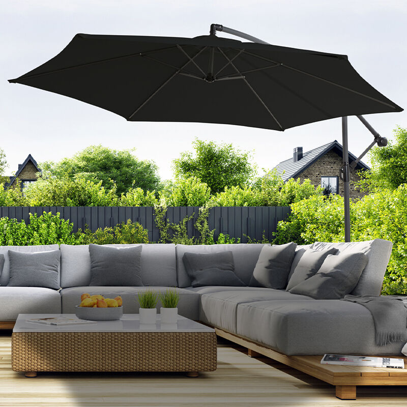 De 909 Outdoor Hangende Parasol in de kleur zwart werpt schaduw over een loungeset.